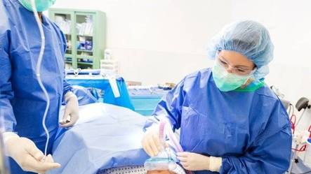 Two healthcare professionals administering anesthesia to patient